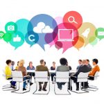 Stock photo of business people around a table with speech bubbles above their heads