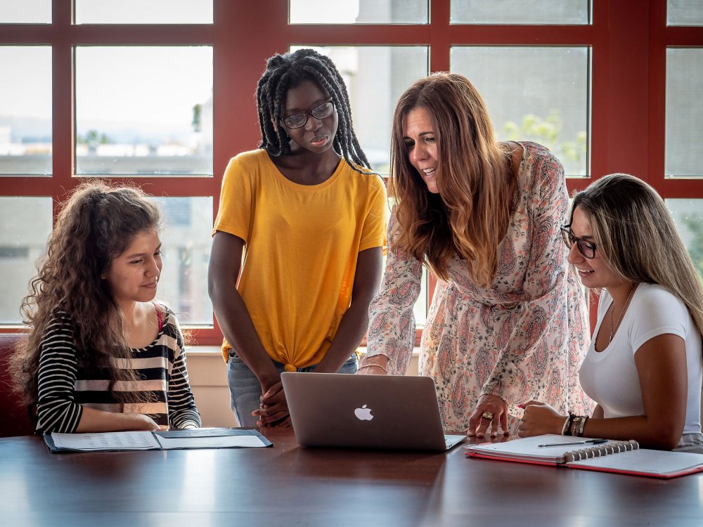 students and professor looking at computer