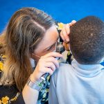 audiology student looks into student's ear with an otoscope