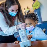 Third year audiology student Rosie Ovadia places a tiny device in a Newark student’s ear for an otoacoustic emission test, which determines cochlear function.