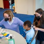 Professor Maryrose McInerney assists audiology student Alyssa Bonapace, in conducting a otoacoustic emission test on a young student in Newark.