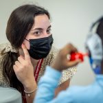 student Nicole Genser is holding a pointed finger up to her ear