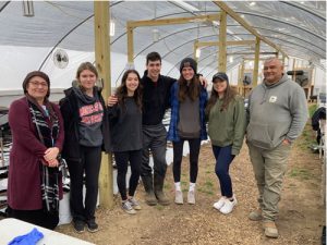 photo of a group of students standing side by side in a large greenhouse