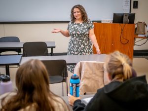 "A woman stands in front of students, gesturing."