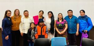 "People dressed in Indigenous clothing stand in a classroom with Antonella Calarota-Ninman."