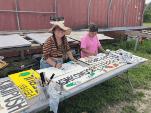 student smiles while painting a sign