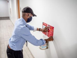 Employee posting sanitizer sign