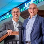 Merli and Radin in front of stock ticker