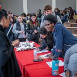 students asking Wamwari questions after class