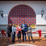 Five people standing in front of ribbon before cutting