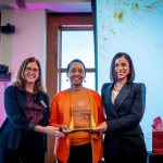 Three women smiling and holding trophy