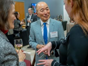 A man in a gray suit and blue tie talks to a person off camera