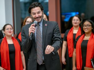President Koppell in a gray suit speaks on a microphone