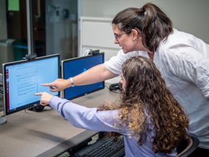 instructor and student pointing at computer monitor
