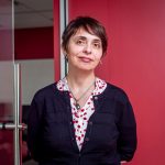 "Professor Anna Feldman stands against a red wall."