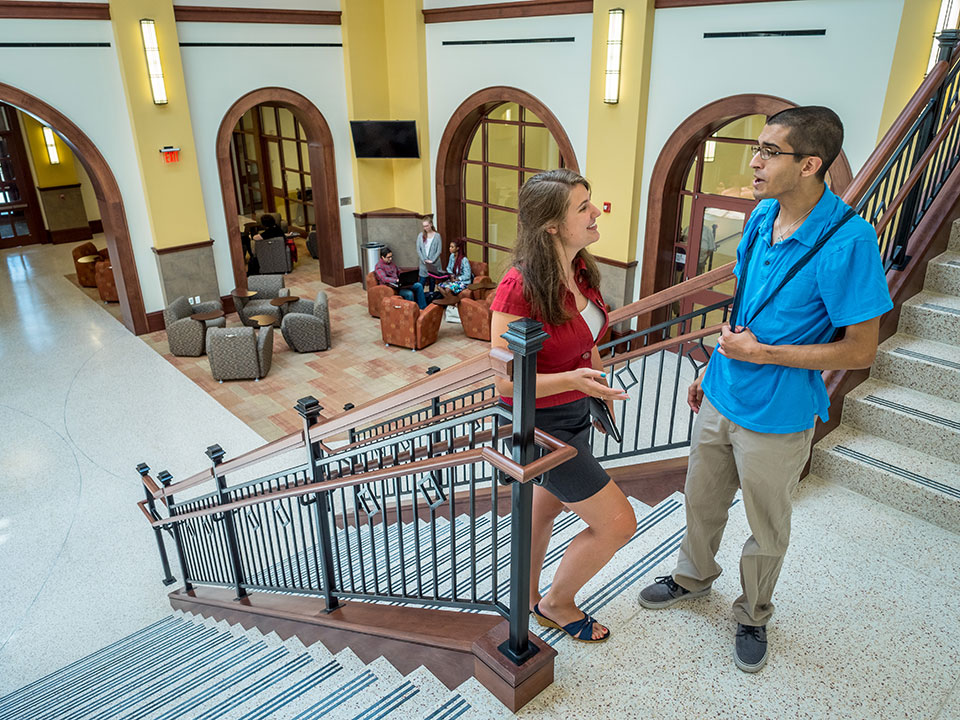 A pair of Montclair State University students chatting in the Feliciano School of Business atrium.
