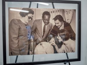 black and white photo in a frame on a easel. in the photo, the people are looking and pointing on a globe