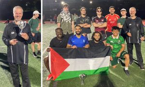 students from winning soccer team pose with flag and trophy