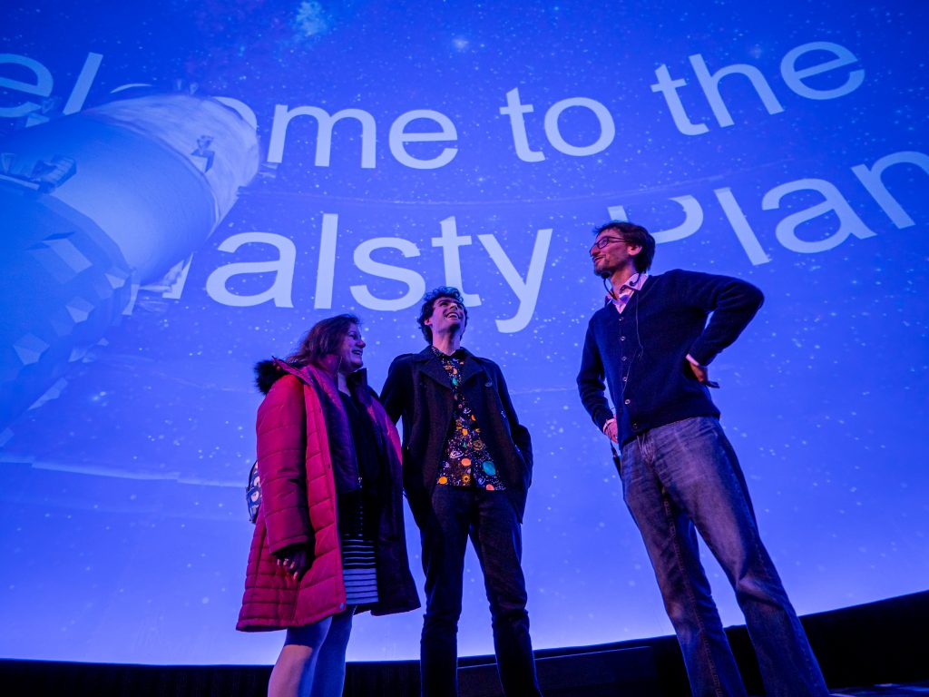 Marc Favata, right, discusses his presentation with Montclair State physics alumnus and current graduate student Robert Onoz BS'22 (center) and his guest.