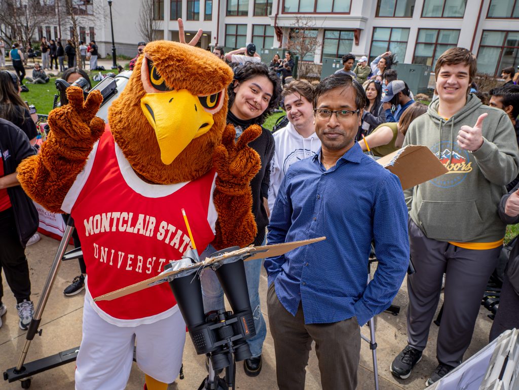 Rocky joins Prof. Shaon Ghosh and physics majors Stephanie Montoya, Elton Ago, and Max Polak---checking out a projected image of the Sun. (Sorry, Rocky, we didn't have eclipse glasses in your size.) [Photo by John LaRosa.]