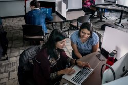 two people looking at a laptop in a computer lab
