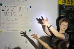 German student making shadow puppets on a whiteboard