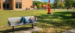Student in outside of Dickson hall lying on bench