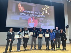 Presenters pose for a group photo on stage.