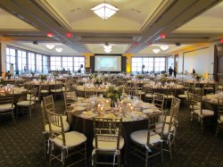The Main Ballroom set up with gold and white chairs and a dining setup.