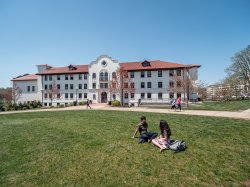exterior shot of Russ Hall on a sunny day with a few students in the quad