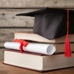 Image of a stack of books with a diploma and a graduation cap.