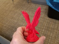 Hand holding a small 3D-printed Red Hawk statue