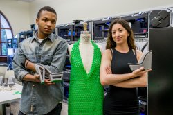 Male and female student pose with 3D printed green dress, and gray shoes