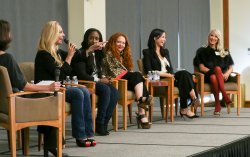Six women in chairs on stage for the panel