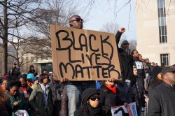 Man holding Black Lives Matter sign amidst protest.