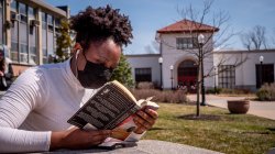 Photo of student reading a book on campus