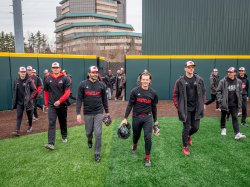Men in black-and-red Montclair baseball uniforms walk onto a field.