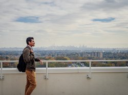 Graduate student standing outside on green roof of CELS overlooking New York City skyline.