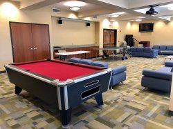 The common area in Sinatra Hall featuring some couches and chairs, a pool table and a television.