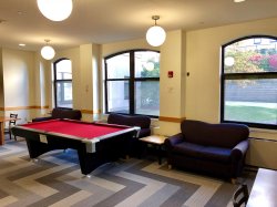 The common area in the Village Apartments with a pool table and some couches.