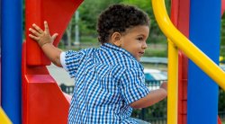 Image of a small child on a playground play structure ready go to down the slide.