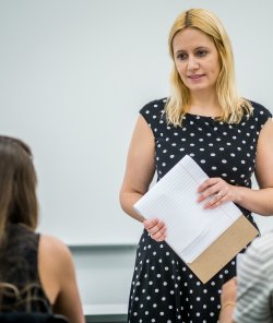 Image of a faculty member, Svetlana Shpiegel, listening to a student talking in a classroom setting.