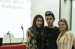 Photo of three students standing together at an event with a Cuban poet.