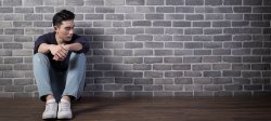 Picture of a person sitting and leaning up against a brick wall
