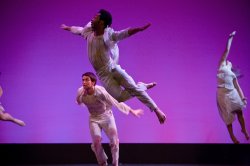 Photo of dancers in white leaping through the air.