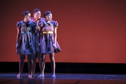 Photo of trio of dancers standing close on stage.