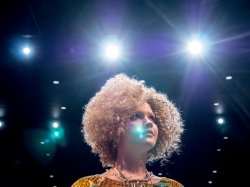 Student Actress performing in production of Hair standing with stage lights in background