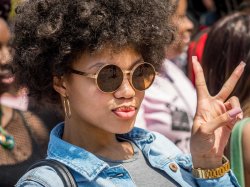 Photo of student on campus wearing sun glasses and displaying a peace sign.