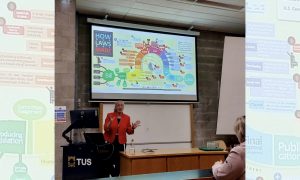 photo of professor Emily Douglas presenting with a slide presentation behind her