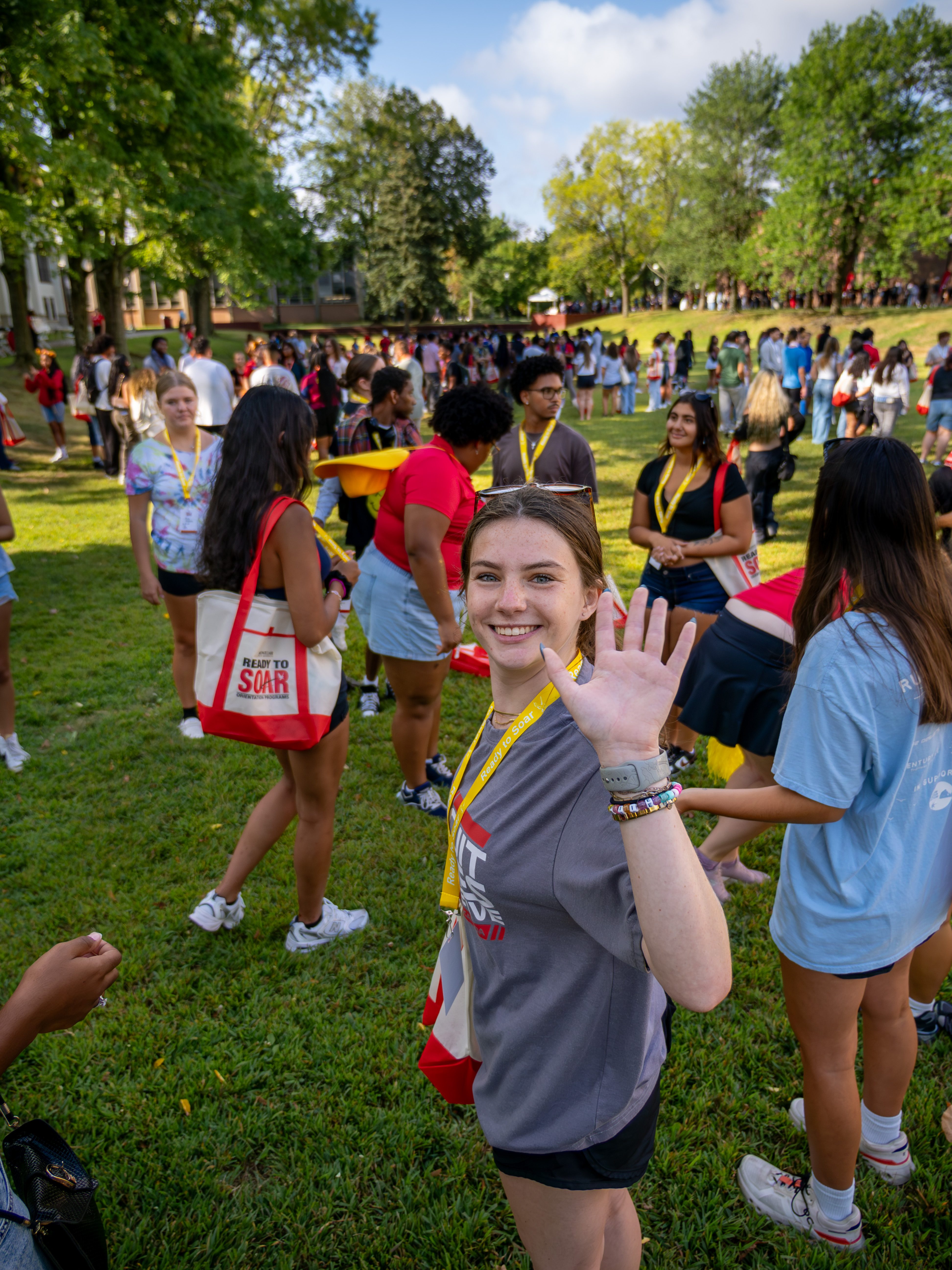 girl waving at the camera in a crowd on Montclair campus.